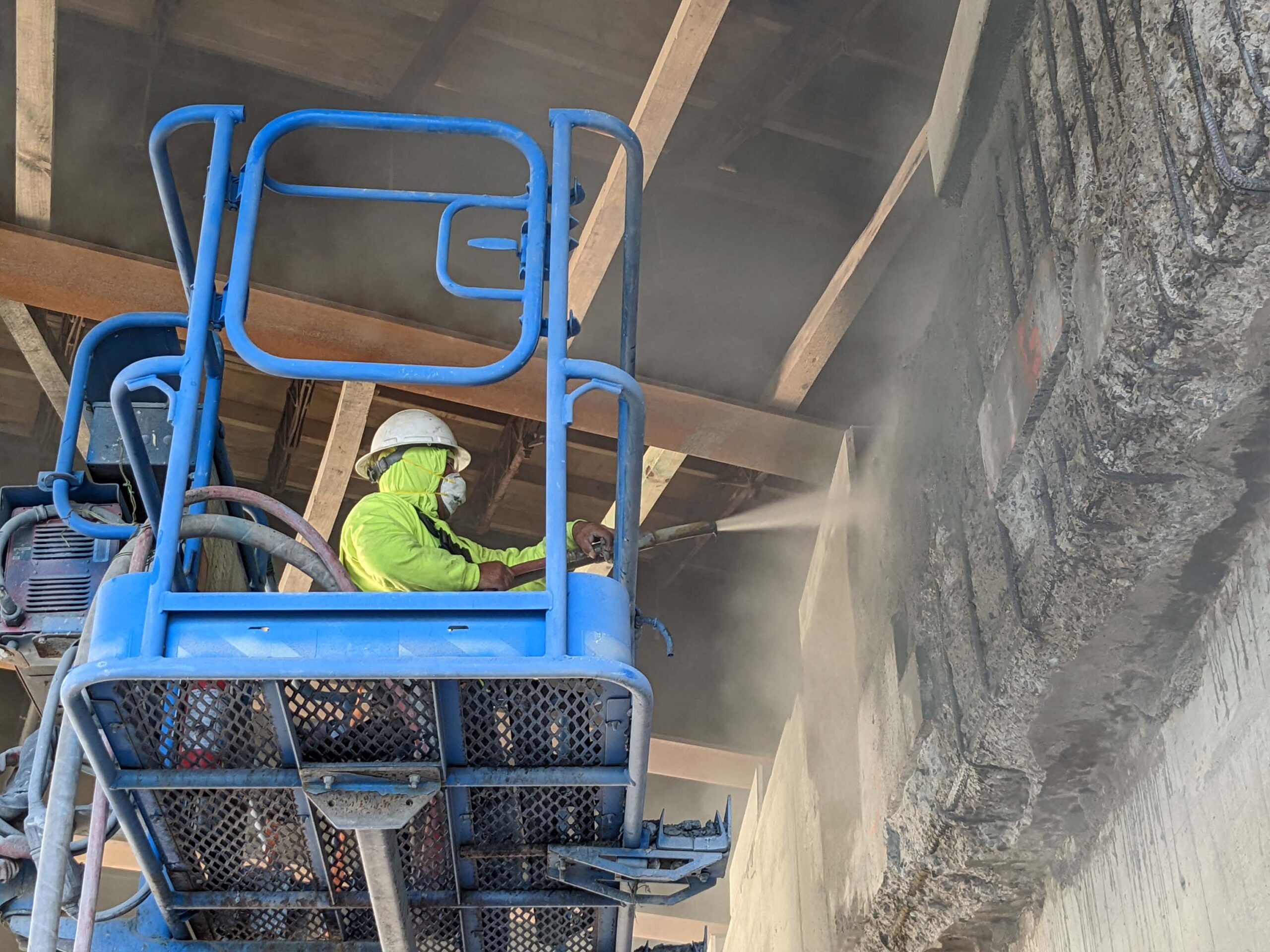 A construction worker repairing a bridge with FasTrac Structural Shotcrete.